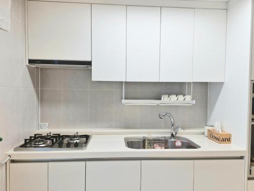 a kitchen with white cabinets and a sink at Stay Dasony in Gyeongju