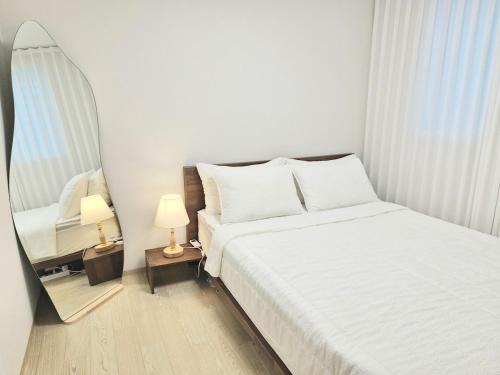 a bedroom with a white bed and a mirror at Stay Dasony in Gyeongju