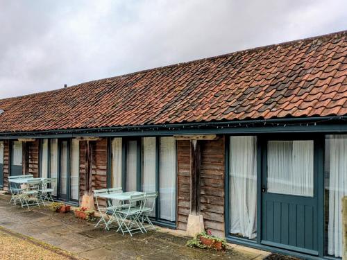 RudloeにあるLower Rudloe Farmの前にテーブルと椅子が置かれた家