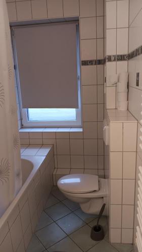 a bathroom with a toilet and a tub and a window at Crew Quartier ALL-INCLUSIVE Serviced Apartment in Krostitz in Krostitz
