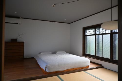 Un dormitorio blanco con una cama y una ventana. en 余韻 奈良宿 - yoinn narayado, en Gojō