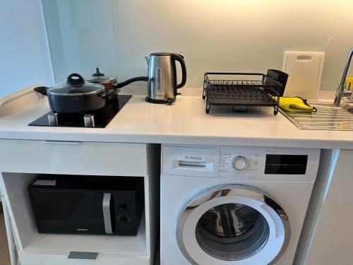 a kitchen counter with a stove and a washing machine at astra sharingla view top floor in Chiang Mai