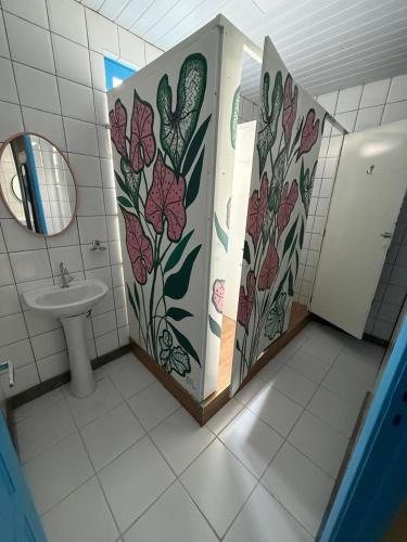 a bathroom with a toilet and a sink with flowers on the wall at General Hostel Belém in Belém
