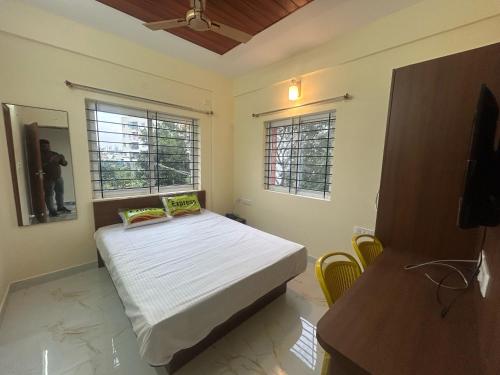 a bedroom with a bed and two windows at Hotel O SRS COMFORTS in Tāvarikere