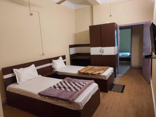 a small room with two beds and a tv at Hotel O SUNLEAF GUEST HOUSE in Dispur