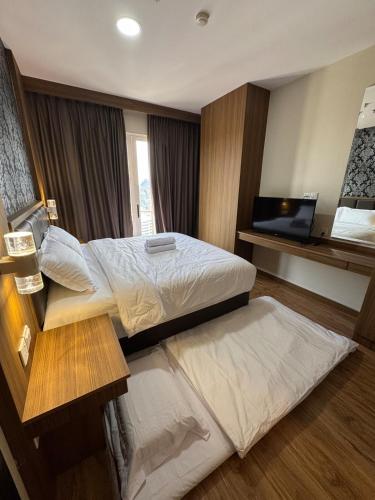 BagamAston Apartment 16-07的一间配有两张床和一台平板电视的酒店房间