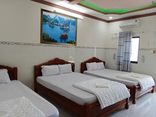 een slaapkamer met twee bedden en een schilderij aan de muur bij Nhà Nghỉ Việt Thắng Dinh Thầy Thím in La Gi