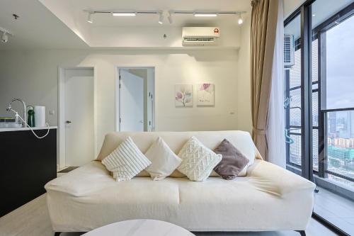 ein Wohnzimmer mit einer weißen Couch mit Kissen in der Unterkunft Trion Kuala Lumpur by Vivid Stay in Kuala Lumpur