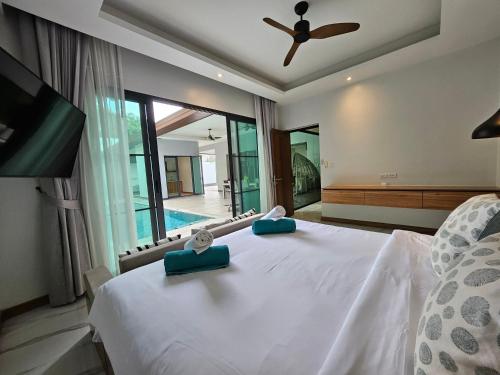 - une chambre dotée d'un lit blanc avec des oreillers bleus dans l'établissement Nicky Villa Luxury Private Haven in BangTao Laguna, à Laguna Phuket