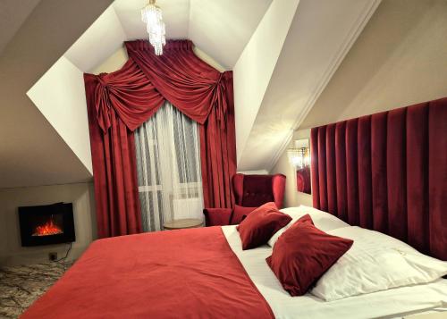 a bedroom with a bed with red curtains and a fireplace at Dworek Nad Stawem & Łaźnia Piwna in Ostrów Mazowiecka