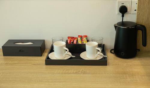 ディグラにあるParadise Foundのマグカップ2個とコーヒーポット1個と箱が入ったトレイ