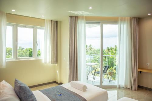 a hotel room with a bed and a balcony at Paradise Found in Dhigurah