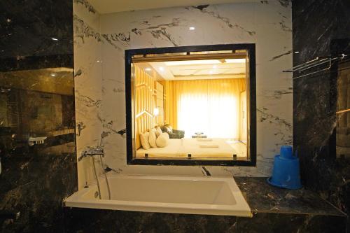 ein Badezimmer mit Badewanne und großem Spiegel in der Unterkunft Prasant Beach Resort Mandarmani in Mandarmani