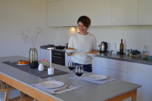 a woman standing in a kitchen holding a plate of food at Nature Rooms cabin in Dzhiviskli