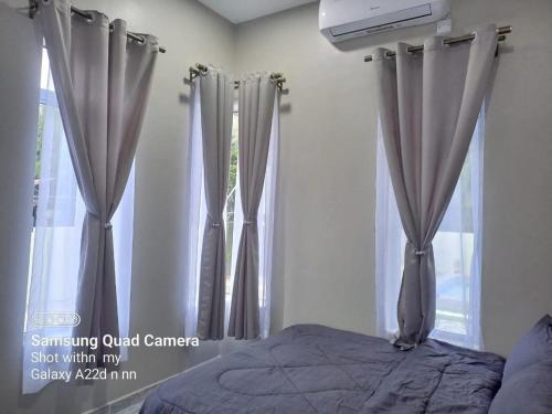 a bedroom with gray curtains and a bed and a window at Teratak Nu'aiman With Pool in Bedung