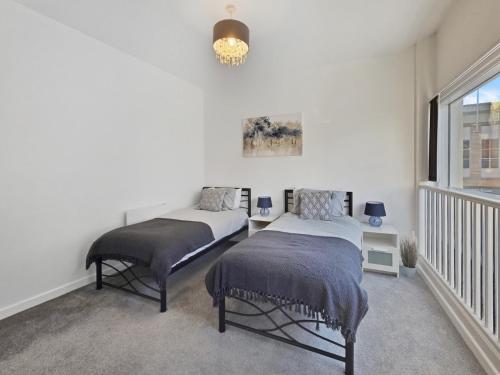 two beds in a white room with a window at Spacious Stylish Apartment in Swindon Town Centre in Swindon