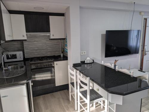 a kitchen with a black counter and a tv on the wall at Olladas de Laxe Apartamento con vistas in Laxe