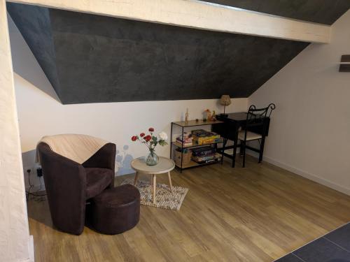 a living room with a chair and a table at Au jardin des pies in Woustviller