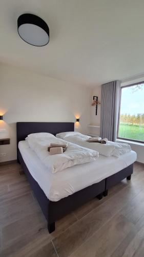 two beds in a room with a large window at Sotteveld in Zwalm