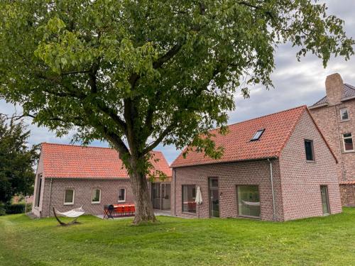 a brick house with a tree in the yard at Sotteveld in Zwalm