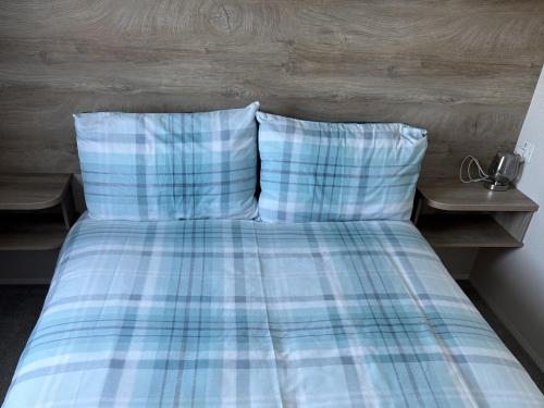a bed with two pillows and a plaid blanket at 30 Wells Close in Cheswick