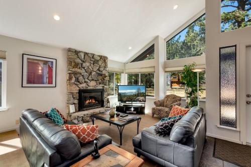 a living room with leather furniture and a stone fireplace at Spacious Riverfront home in Nebelhorn
