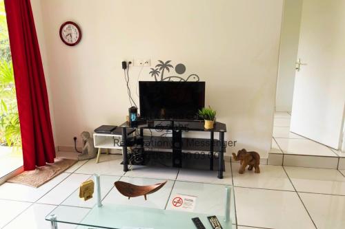 a living room with a tv and a glass table at Villa Karo Coco in Saint-Leu