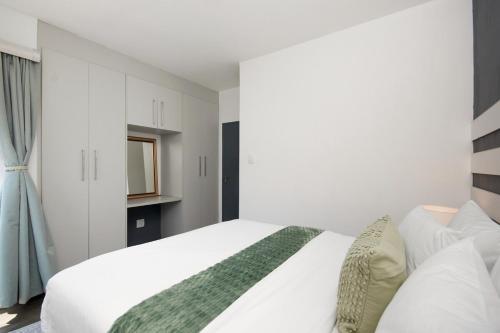 a bedroom with a white bed with a green blanket at The Atrium, Sandton Apartment in Johannesburg
