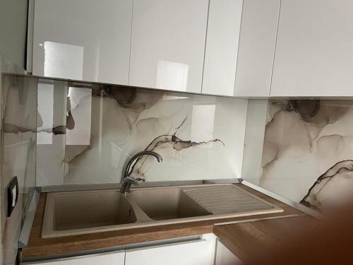 a kitchen with a sink and white cabinets at Amber Comfort Home in Lushnjë