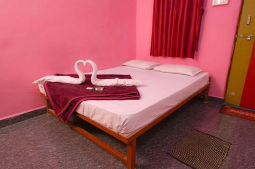 a pink bedroom with a bed with two swans on it at kali river view in Dandeli