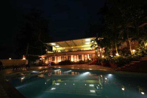 a building with a swimming pool at night at kali river view in Dandeli