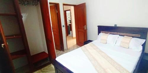 a bedroom with a bed with white sheets and a mirror at Mike's HOUSE in Yaoundé