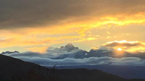 a painting of a sunset with clouds and mountains at Gîte de montagne Las Trinquades in Boussenac