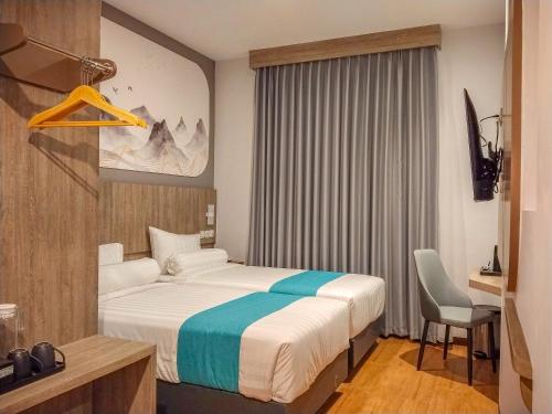 a hotel room with a bed and a chair in it at Front One Luxe Hotel Solo in Solo