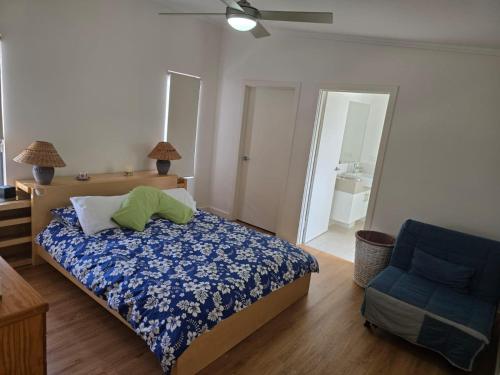 ein Schlafzimmer mit einem Bett und einem blauen Stuhl in der Unterkunft Harry's Place in Lancelin