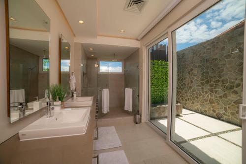 a bathroom with two sinks and a large window at Casa Ohana 5 bdrs ocean view in Los Suenos in La Mona