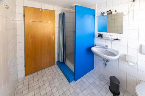 baño con puerta de ducha azul y lavamanos en Goldiger Hirsch B&B mit Kochmöglichkeiten, en Immenstadt im Allgäu
