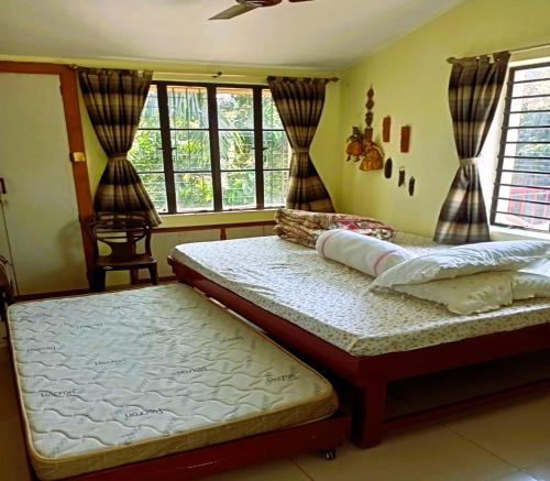 サンティ・ニケタンにあるARANYAK Homestayの窓が2つある部屋にベッドが2つある