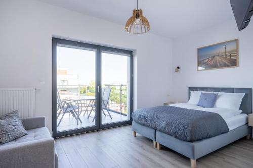 a bedroom with a bed and a couch and a balcony at S1 Apartamenty in Rewa
