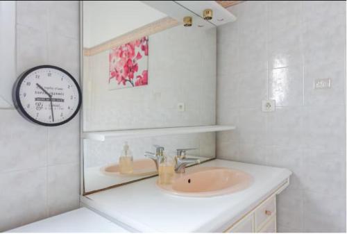 ein Badezimmer mit einem Waschbecken und einer Uhr an der Wand in der Unterkunft logement indépendant avec jardinet in Bouc-Bel-Air