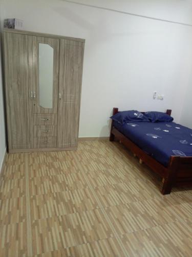 een slaapkamer met een bed en een houten kast bij Chambre et Salon in Agboogba