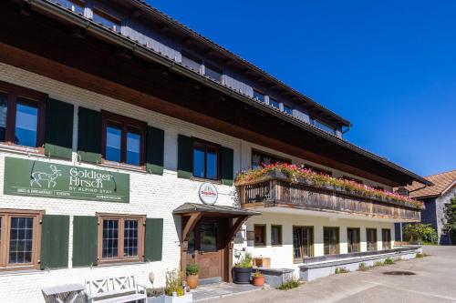 a building with a balcony with flowers on it at Goldiger Hirsch Pension mit Gemeinschaftsküche in Immenstadt im Allgäu