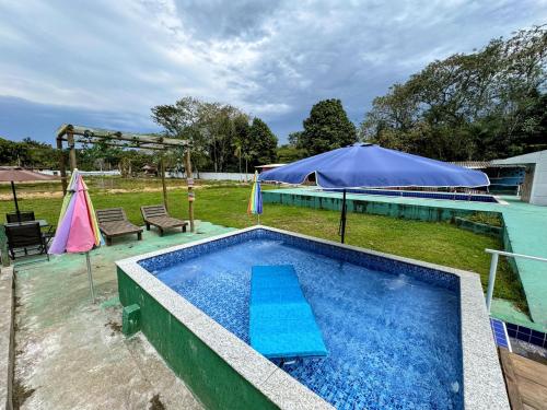a swimming pool with a table and a tent at Suítes Ohana in Peruíbe