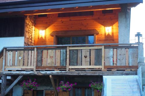 a wooden house with a balcony with flowers on it at Chez Julie in Thollon
