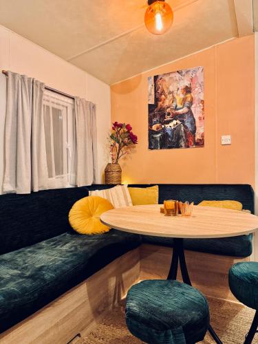 a living room with a table and a couch at Tante Truus - Gezellig huisje op kindvriendelijk vakantiepark met zwembad in Hoenderloo