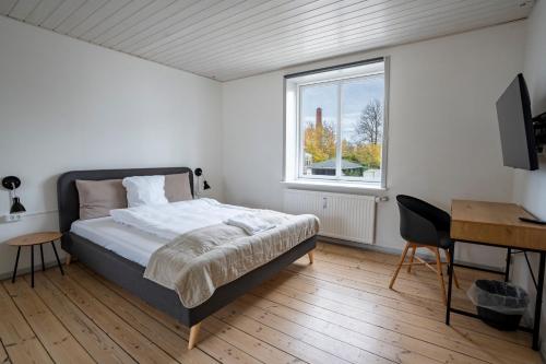 a bedroom with a bed and a desk and a window at City Apartments in Holstebro