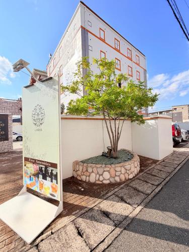 a sign and a tree in front of a building at hotel lindos ホテルリンドス in Okayama