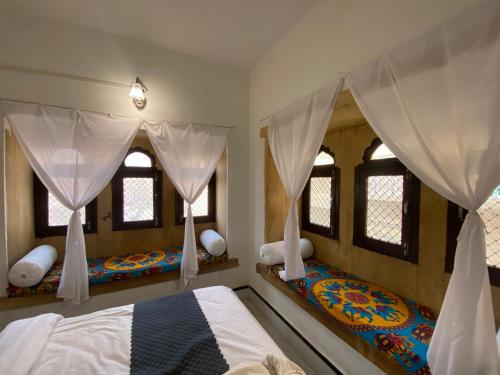 a bedroom with two beds with curtains and windows at Hotel Heaven In Jaisalmer in Jaisalmer
