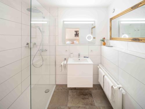 a white bathroom with a shower and a sink at Romantik Hotel Landhaus Bärenmühle in Frankenau