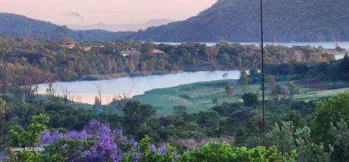 a lake in the middle of a valley with trees at 129B African Bushveld in Buffelspoort